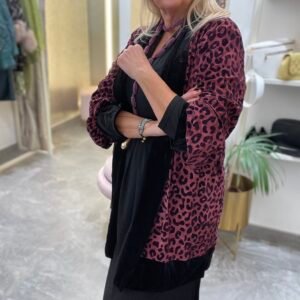 Mujer con vestido negro y kimono de terciopelo en color rosa con estampado de leopardo. Lleva un collar de cuentas rosadas.