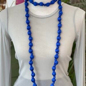 Collar doble de cuentas grandes envueltas en tela azul intenso, mostrado en un busto de tela gris claro.