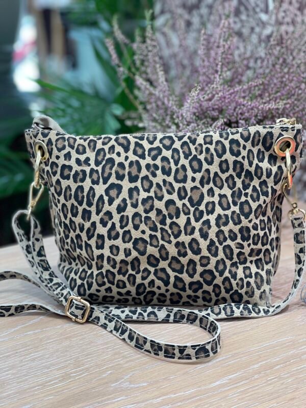 Bolso pequeño con estampado de leopardo en tonos beige y negro, con asa desmontable a juego, sobre una superficie de madera clara.