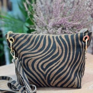 Bolso pequeño con estampado de cebra en tonos marrón y negro, con asa desmontable a juego, sobre una superficie de madera clara.