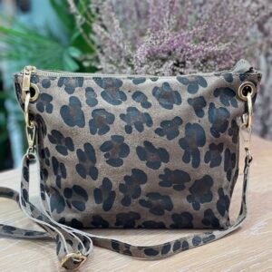 Bolso pequeño con estampado de manchas en tonos marrón oscuro sobre un fondo beige, con asa desmontable a juego, sobre una superficie de madera clara.