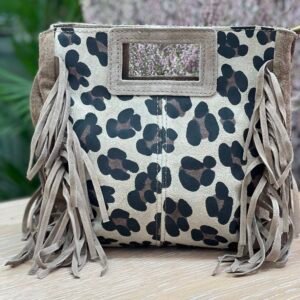 Bolso de mano en tonos beige con estampado de manchas tipo leopardo en negro y marrón, con flecos de gamuza en los laterales y un asa rígida rectangular.
