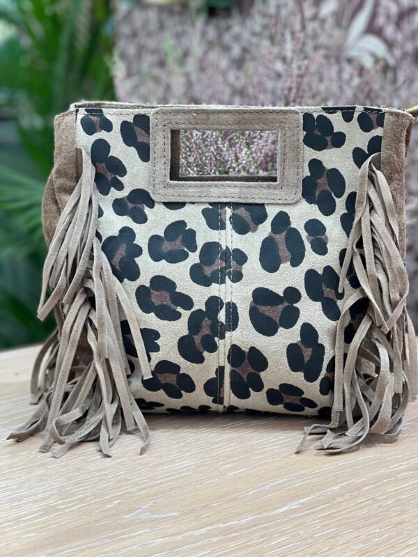Bolso de mano en tonos beige con estampado de manchas tipo leopardo en negro y marrón, con flecos de gamuza en los laterales y un asa rígida rectangular.
